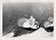 Young man sitting on a rock partially submerged in water